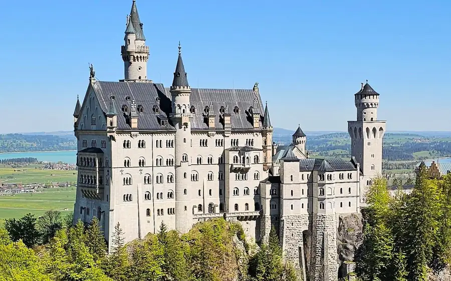 Neuschwanstein Castle auf seinem Felsgrat, von der Seite über den Bäumen gesehen